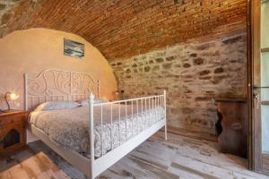 a bedroom with a white bed and a brick wall at Casale La Selva Cottege piccolo in Piano Porlezza