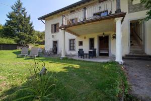 a house with a porch and chairs in the yard at Casale La Selva Cottege piccolo in Piano Porlezza