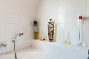 a white bathroom with vases sitting on a shelf at Escapade Sérénité - Les Alignements in Carnac +14 photos