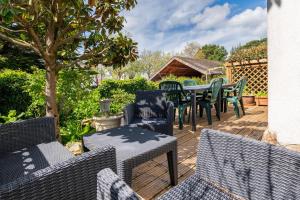 a deck with chairs and tables and a tree at Escapade Sérénité - Les Alignements in Carnac