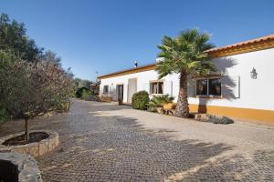 a cobblestone street in front of a house with palm trees at Casa Palma in Paderne