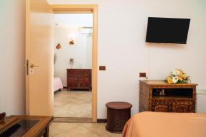 a bedroom with a bed and a television on a wall at Garden Cottage I Dammusi - Arancio in Castelmola