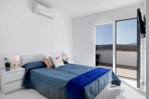 a white bedroom with a bed and a large window at Coral 5 in La Santa