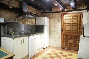 a kitchen with white cabinets and a wooden door at La Platería I in Mambrilla de Castrejón
