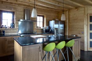 a kitchen with a large island with green bar stools at Houten villa Albert in Den Ham
