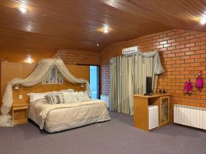 a bedroom with a bed and a brick wall at A Cabanha in Caçador