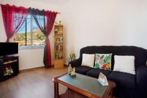 a living room with a black couch and a table at Casa Orquidea T3 in Ponta do Sol