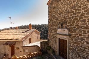 an old stone building with a door next to a building with trees at Beb Pulcino Nero Scrofiano in Scrofiano