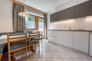 a kitchen with white cabinets and a table and chairs at App Sonne Nr 16 in Lutago