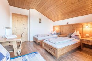a room with two beds and a wooden ceiling at Schildberghof Schlernblick in Kastelruth