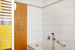 a white tiled bathroom with a bath tub at Ferienwohnung Tannenblick 7-4 in Oberhof +17 photos