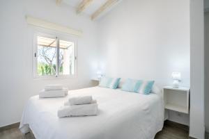 a white bedroom with a large white bed with blue pillows at Ses Oliveres in Pollença