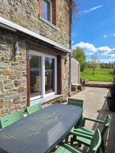 a table and chairs in front of a stone house at Ma maison de famille in Saint-Hubert