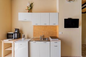 a kitchen with white cabinets and a sink at La rimesa di Tittì - Tittì in Alezio +13 photos
