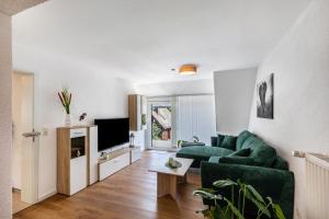 a living room with a green couch and a tv at Ferienwohnug New Look in Geisenheim