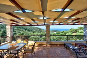 a patio with tables and chairs and a large window at Villa Casa Bianca Purple Apartment in Gaios