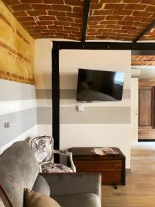 a living room with a couch and a tv on a wall at Le Zucche Vuote in Quargnento