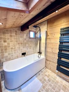 a bath tub in a bathroom with wooden walls at Chalet Mouflon - Vue lac imprenable in Thollon +15 photos