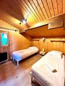 two beds in a room with a wooden ceiling at Chalet Mouflon - Vue lac imprenable in Thollon