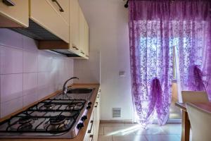 a kitchen with a stove and a window with purple curtains at Appartamento Andromeda B2 in Bibione