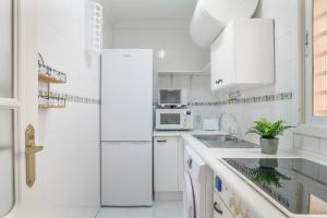 a white kitchen with white cabinets and a refrigerator at Apartamento a pie de playa in Barbate