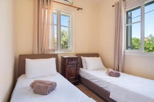 two beds in a room with two windows at Avra in EFL