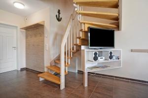 a living room with a staircase with a flat screen tv at Ferienhaus Seepferdchen in Dranske
