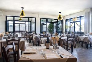 a dining room with tables and chairs and windows at Hotel Genzianella in Cervia