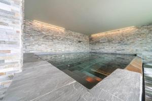 a swimming pool in a room with a brick wall at Resort Style Apartment in Perledo