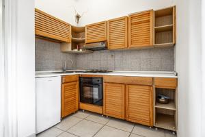 a kitchen with wooden cabinets and a white dishwasher at La Capannuccia A in Ansedónia