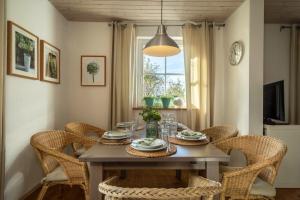 a dining room table with wicker chairs and a clock at Ferienhaus Landlust-Karsee in Wangen im Allgäu