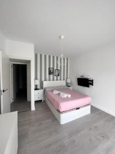a white bedroom with a pink bed and a television at Casa Mayra in Los Caparroses +19 photos