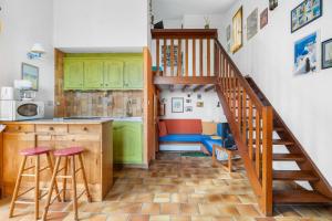 a kitchen with green cabinets and a spiral staircase at Bastidon Avec Terrasse Vue Mer in Carqueiranne
