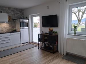 a kitchen with white appliances and a tv on a wall at Tobel Lounge in Sigmarszell