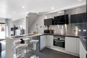 a kitchen with white cabinets and a counter with stools at Be Glow Home in Alvor +16 photos