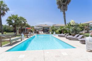 a swimming pool with lounge chairs and palm trees at Lointaines escapades in Perpignan