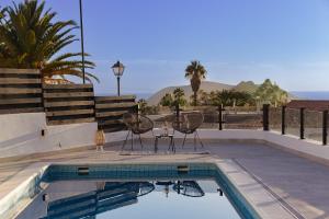 a swimming pool with two chairs and a table next to it at Villa La Blanca in Arona