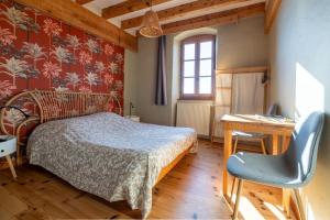 a bedroom with a bed and a desk and a chair at La Chastanha in Saint-Symphorien-de-Mahun