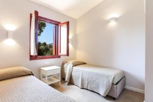 two beds in a room with a window at La casa di Debora in San Teodoro