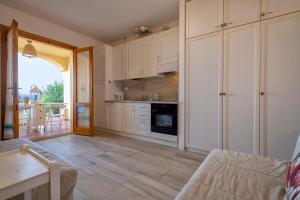 a kitchen with white cabinets and a living room at Relax Space in Cascabraga
