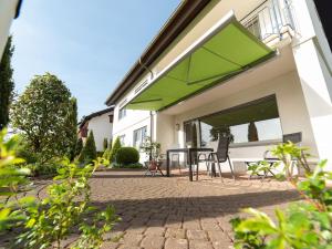 a patio with a table and a green umbrella at Ferienwohnung Pusteblume in Kappelrodeck