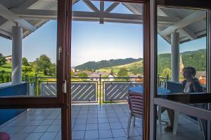 a woman sitting at a table on a balcony at Ferienwohnung Echle in Oberharmersbach +2 photos