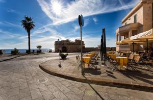 Eine Gruppe von Stühlen und Tischen auf einer Terrasse in der Nähe des Meeres in der Unterkunft Alghero Old Town Charm - Sardinia in Alghero