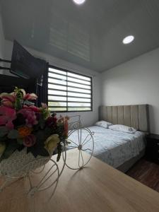 a bedroom with a bed and a table with flowers at 306ApartaesudioRomance in Arauca