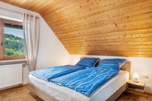 a bedroom with a wooden ceiling and a bed with blue pillows at Haus Grünblick in Münstertal
