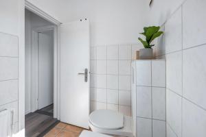 a white bathroom with a toilet and a plant at Ferienwohnung mit Dachterrasse in Heide +21 photos