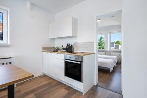 a kitchen with white cabinets and a table and a bed at Ferienwohnung mit Dachterrasse in Heide
