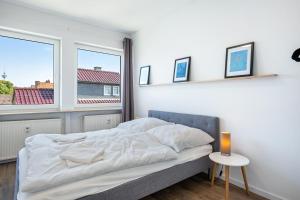 a bedroom with a bed with white sheets and a window at Ferienwohnung mit Dachterrasse in Heide