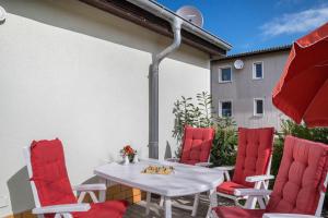 a patio with a white table and red chairs at Strandnaher Bungalow in Dierhagen