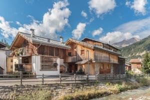 a wooden house in the mountains with a fence at Appartamento Ciasa in Pozza di Fassa